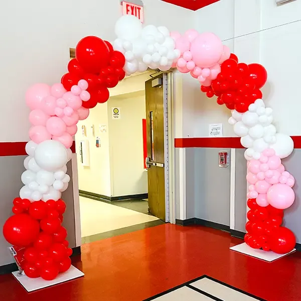 Arco de globos rojo, blanco y rosa enmarcando una puerta