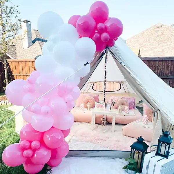 Guirnalda de globos fucsia, rosa y blanco sobre una carpa bell al aire libre