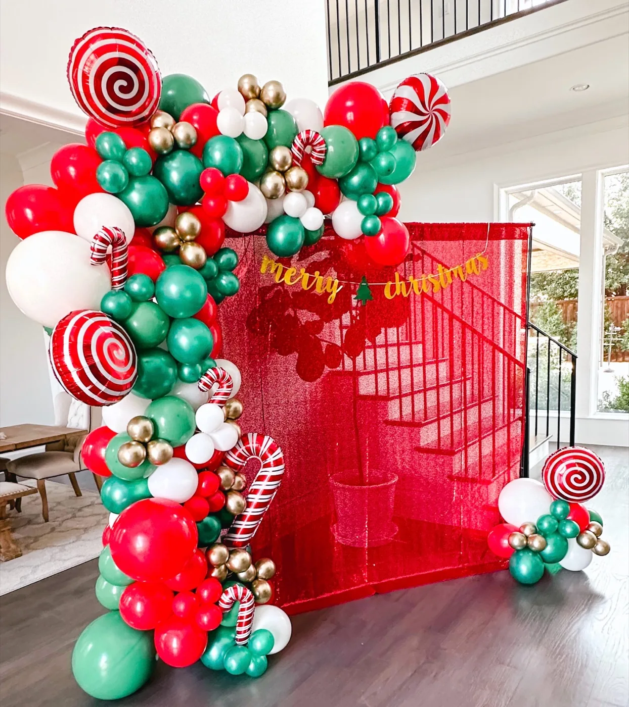Guirnalda navideña de globos rojos, verdes y dorados con globos de bastón de caramelo alrededor de un fondo rojo de lentejuelas