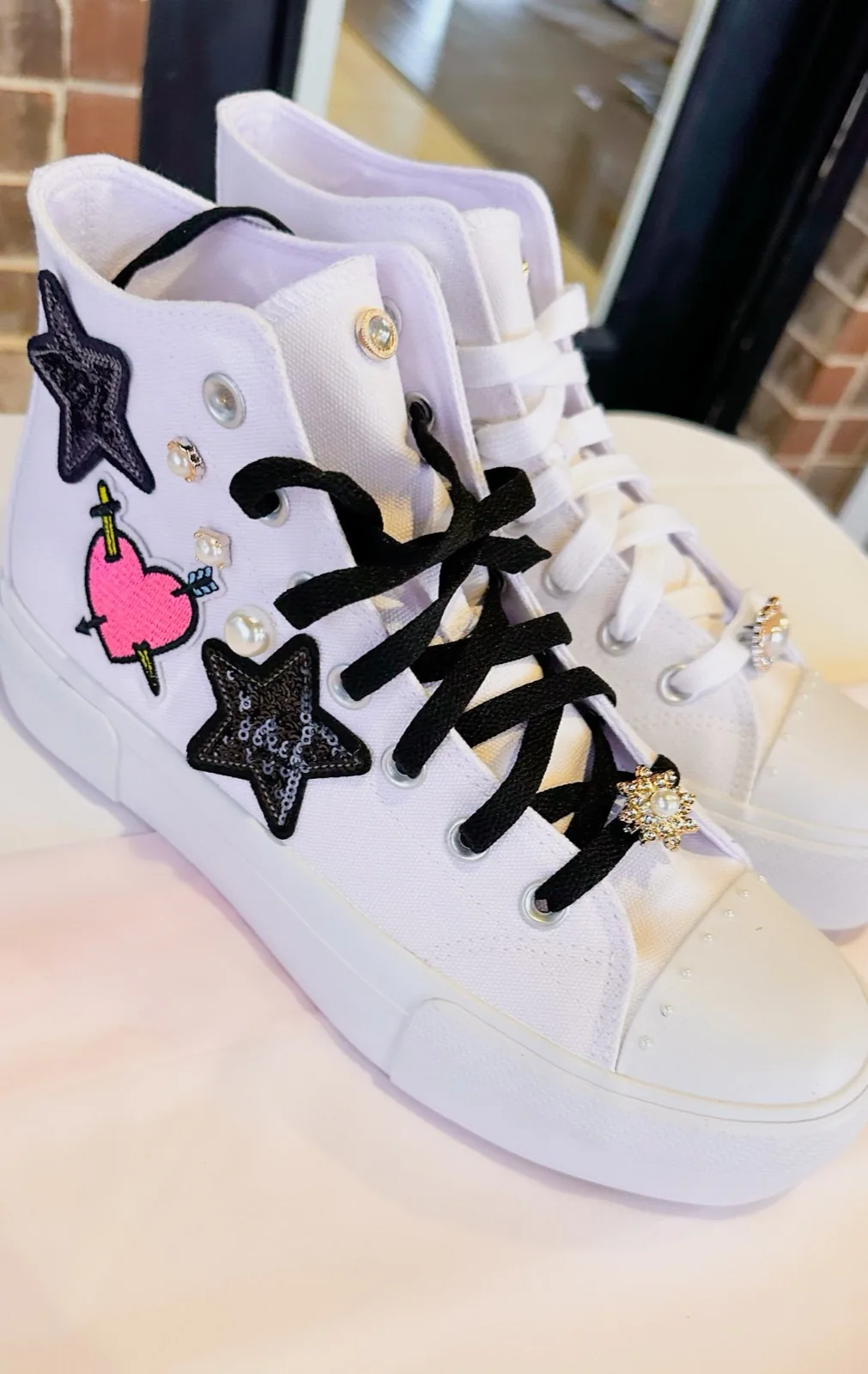 Sneakers decorated with sequin stars, a heart patch and black laces
