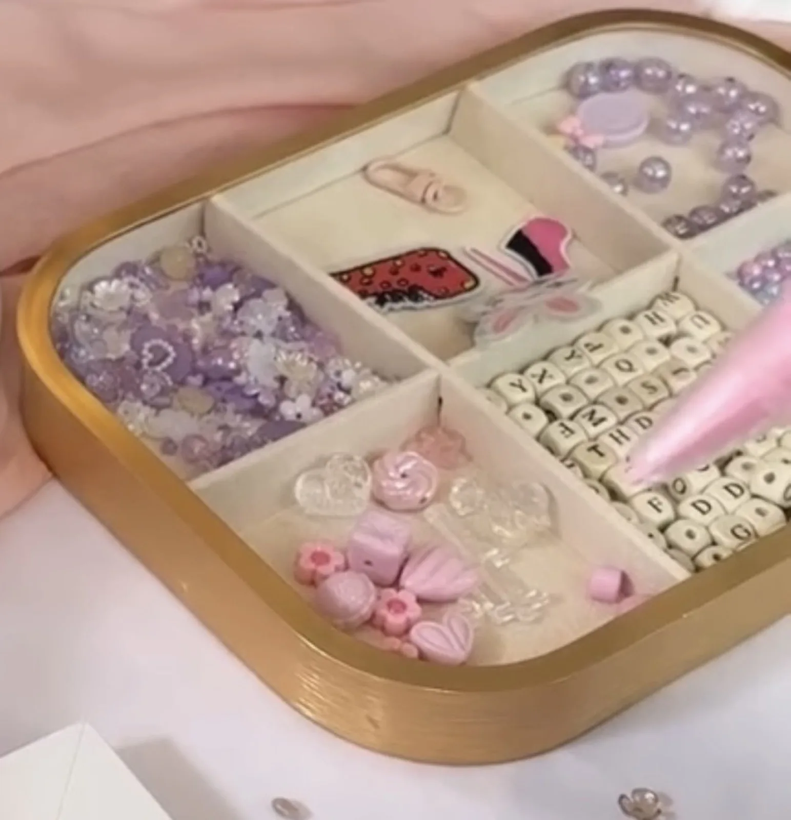 Gold tray of charms, beads and gems for decorating