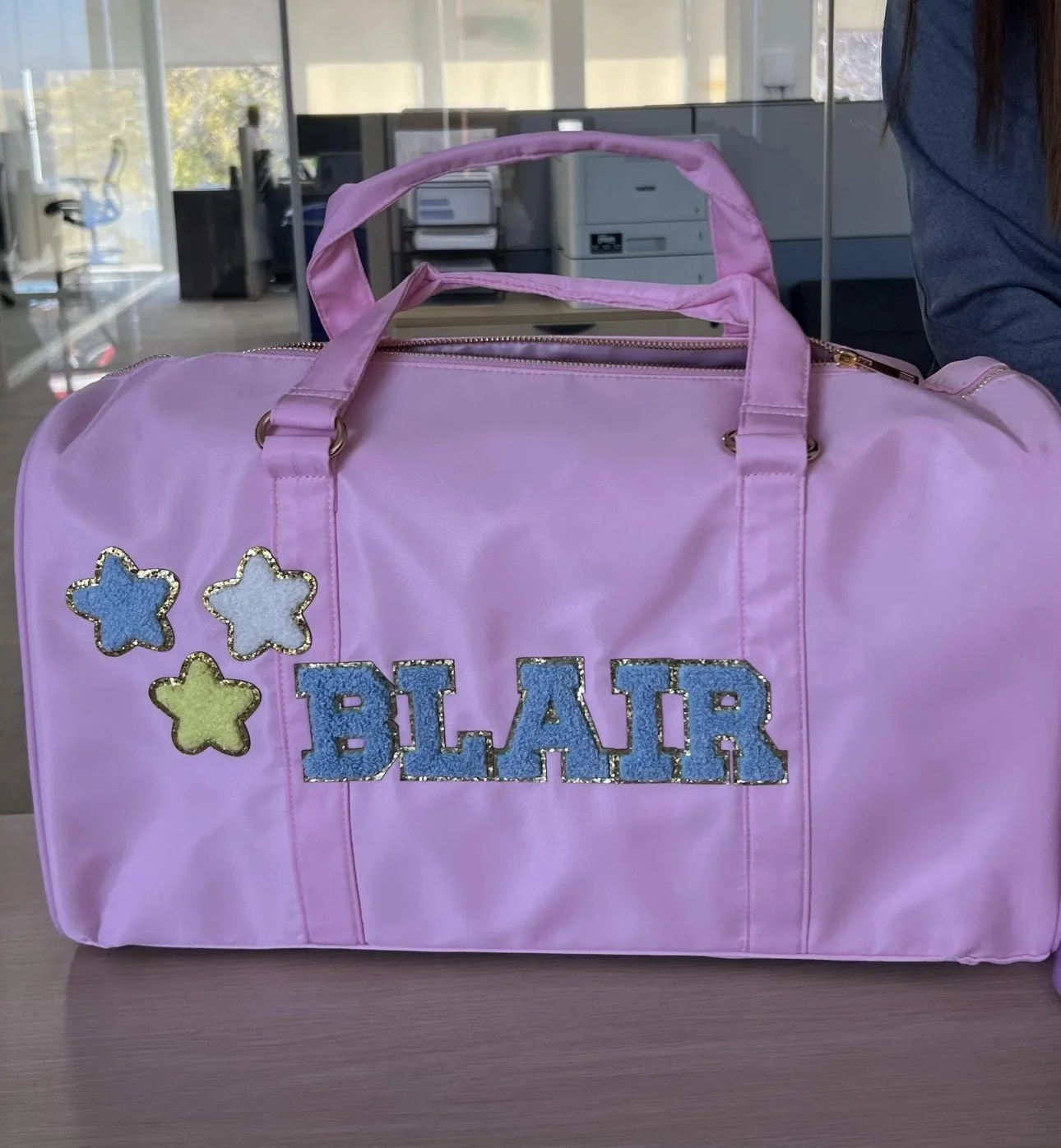 Pink duffel bag personalized with a name and three star patches