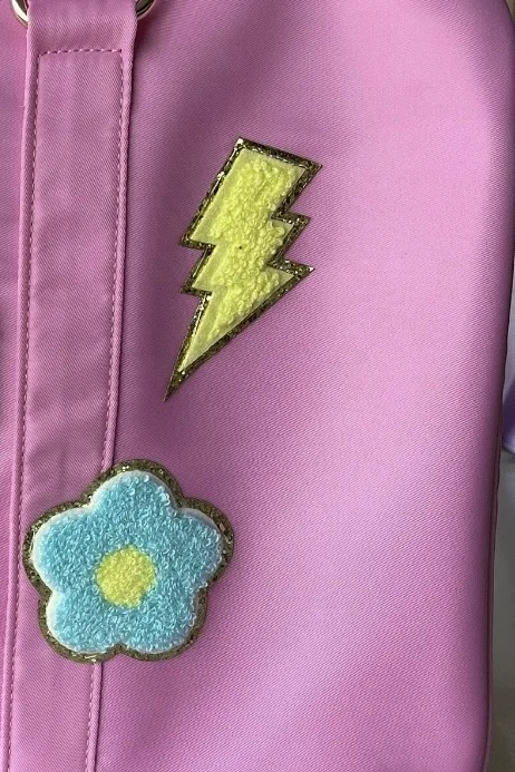 Close up of lightning bolt and flower patches on a pink duffel bag