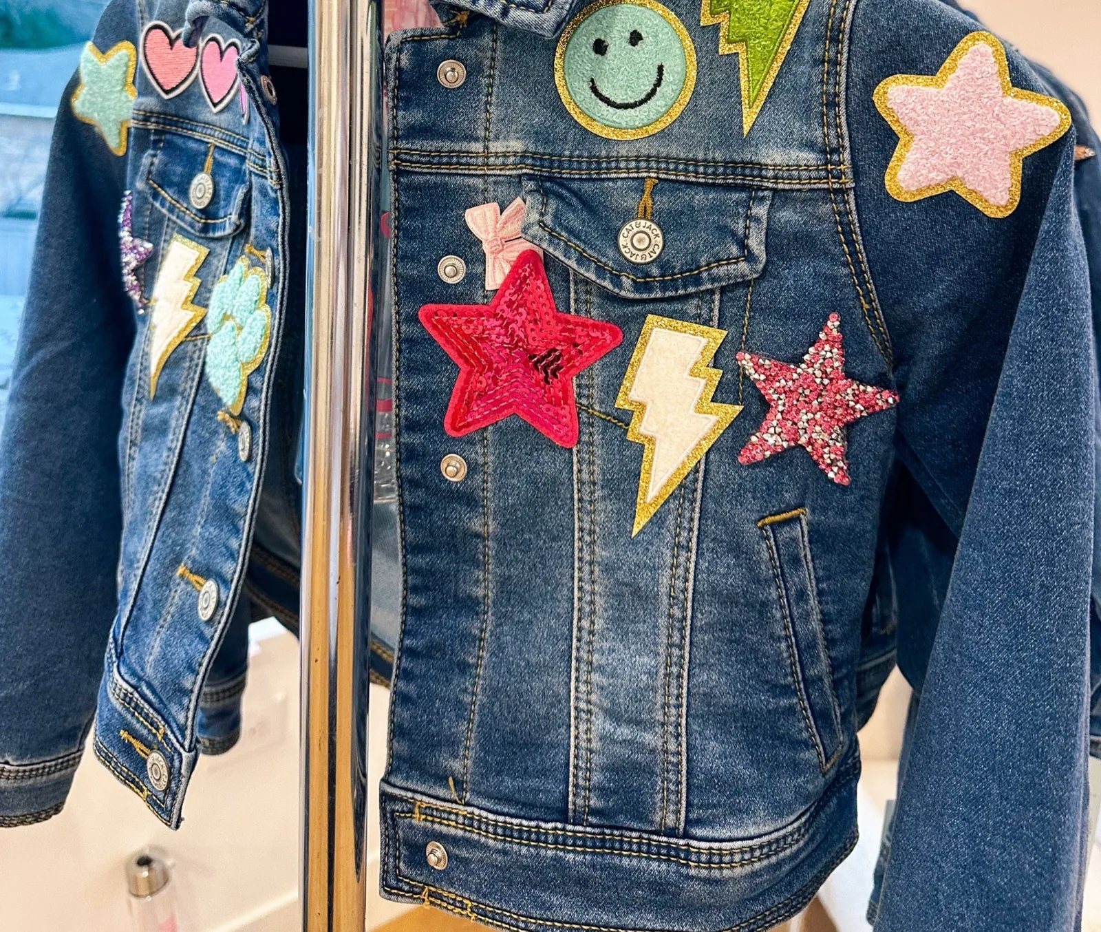 Denim jacket decorated with smiley face, lightning bolt and star patches