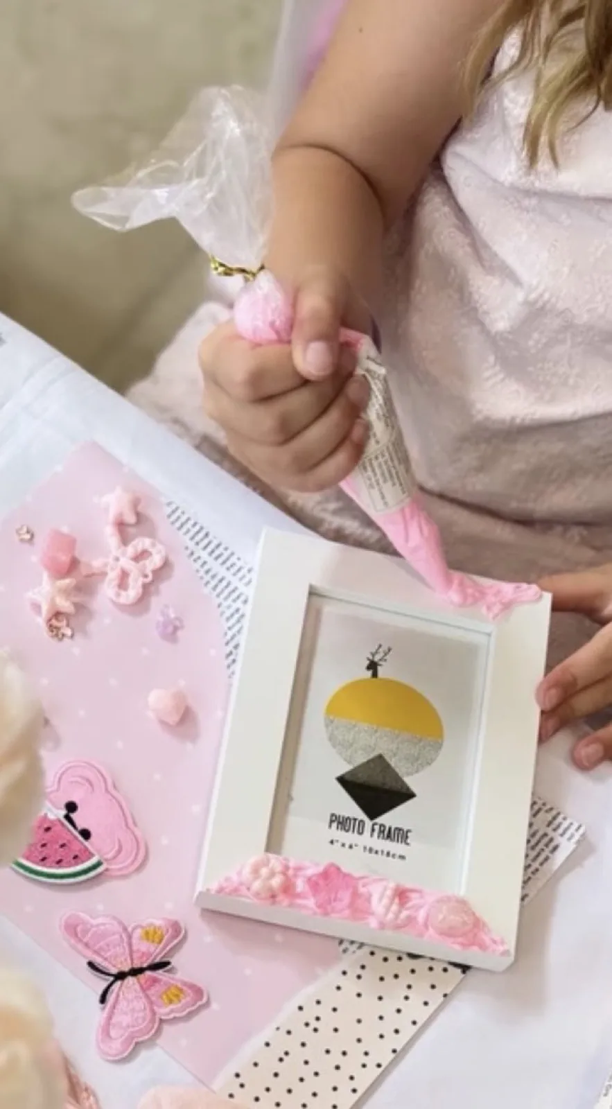 A guest piping pink frosting onto a keepsake surrounded by charms