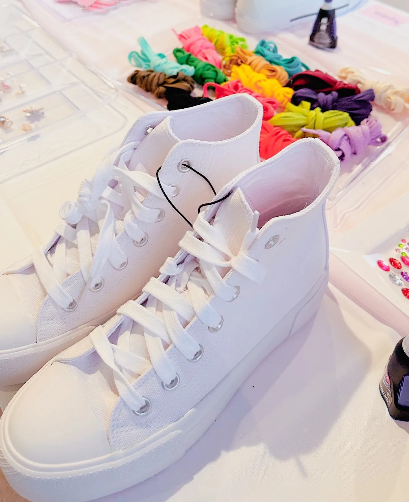 White canvas sneakers ready to decorate, with colorful laces on the workshop table